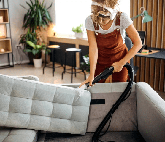 women cleaning sofa with vaccum cleaner